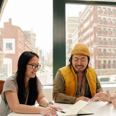 Two people happily working at a desk in an office.