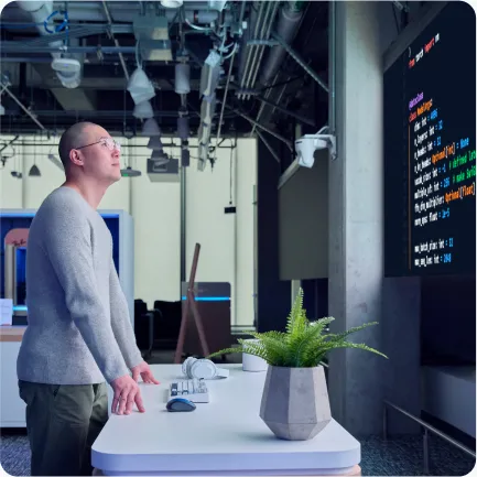 A man in an office looking at code for Research on a large projected screen.